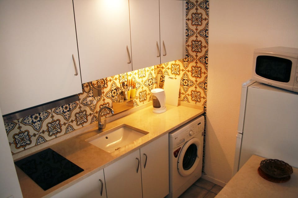 Kitchen equipped with a Microwave, Washing Machine, Electric stove, Kettle.
