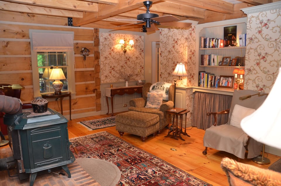 Living room--3-sided view, glass-front wood stove, reading lamps, books & games.