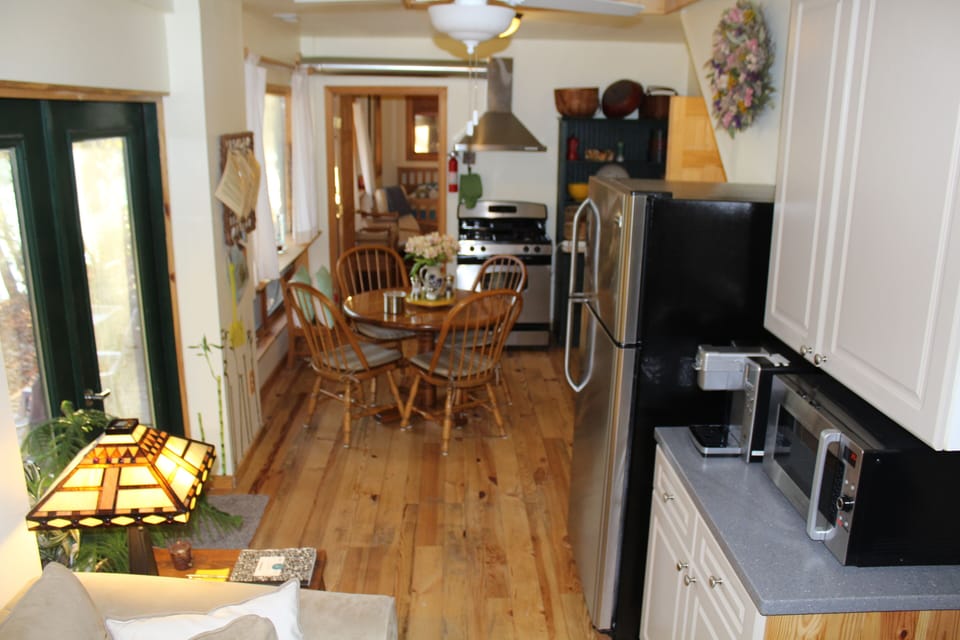 View of kitchen and dining area with entrance & picture windows on left.