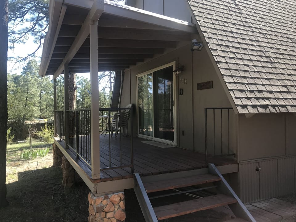 Front porch with table and chairs. Lots of trees on acre lot.