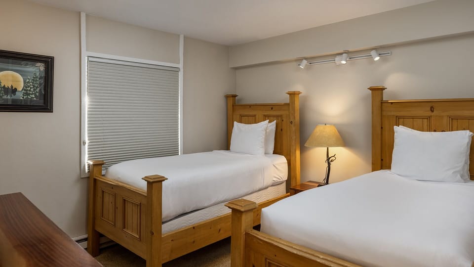 Settle into cozy twin beds with crisp white linens and rustic wood frames, perfect for family getaways or friends traveling together.