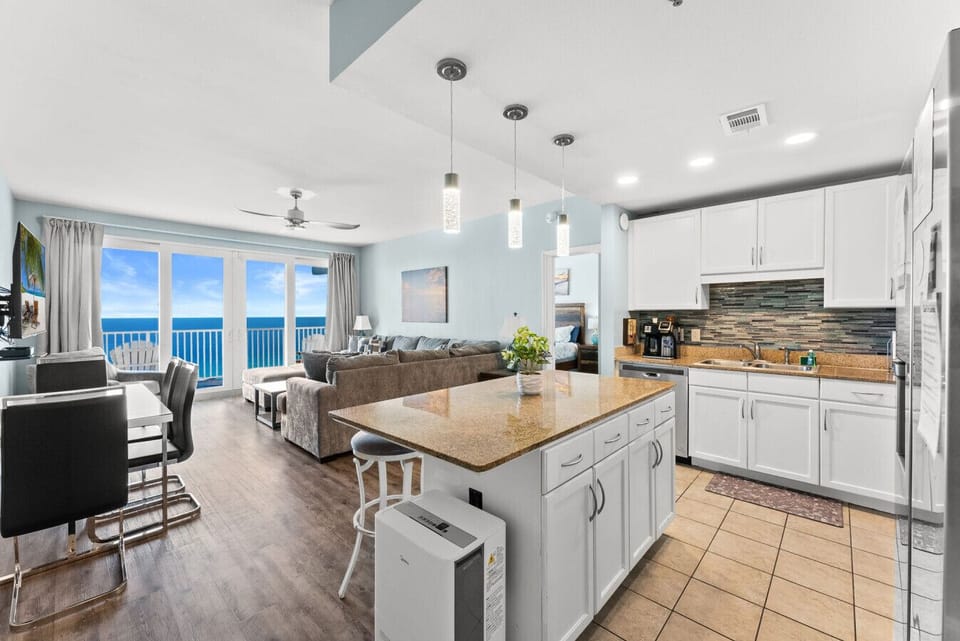 Open-concept living, dining, and kitchen area overlooking the Gulf through floor-to-ceiling windows.
