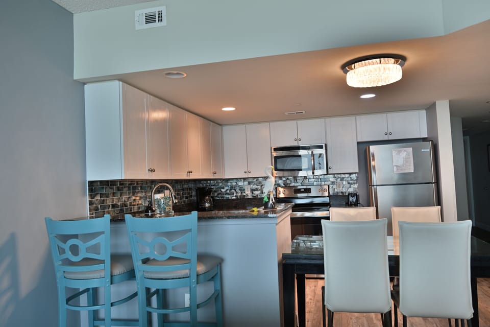 Modern kitchen with white cabinets, stainless appliances & cozy dining area.