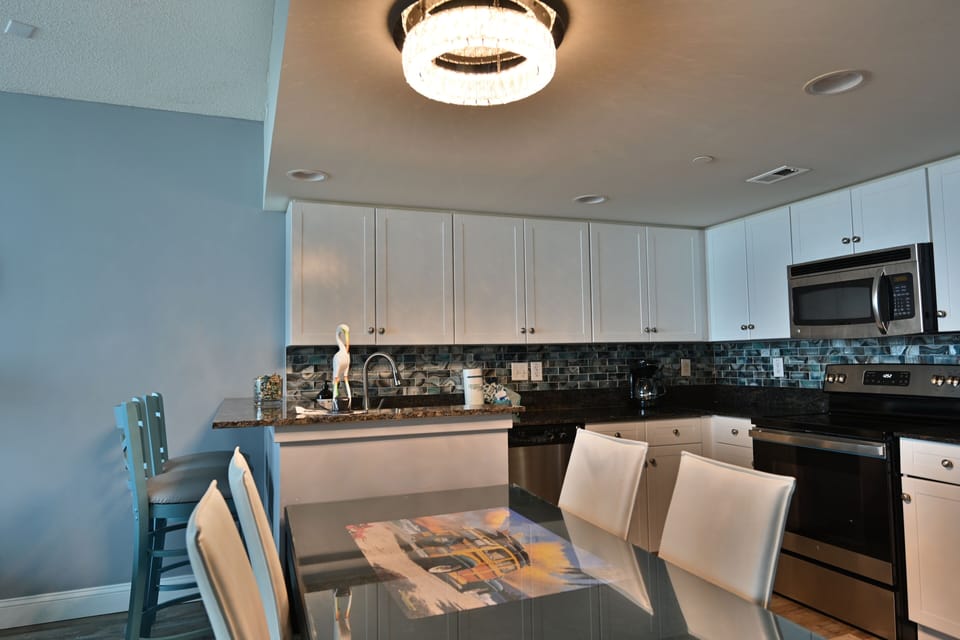 Modern kitchen & dining with white cabinets, stainless appliances & chic decor.