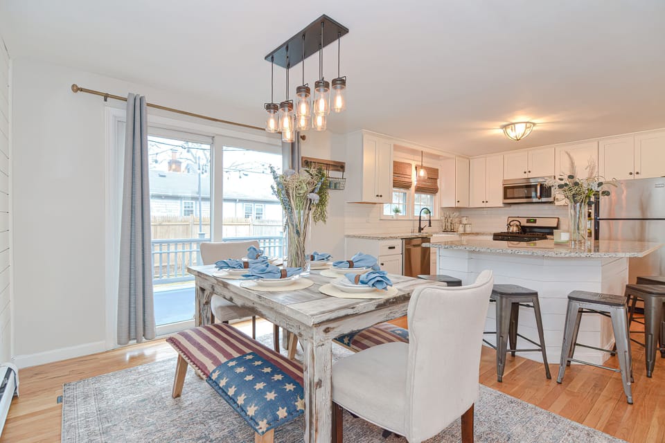 Kitchen & Dining — White cabinets, island seating, and a table set for the group.