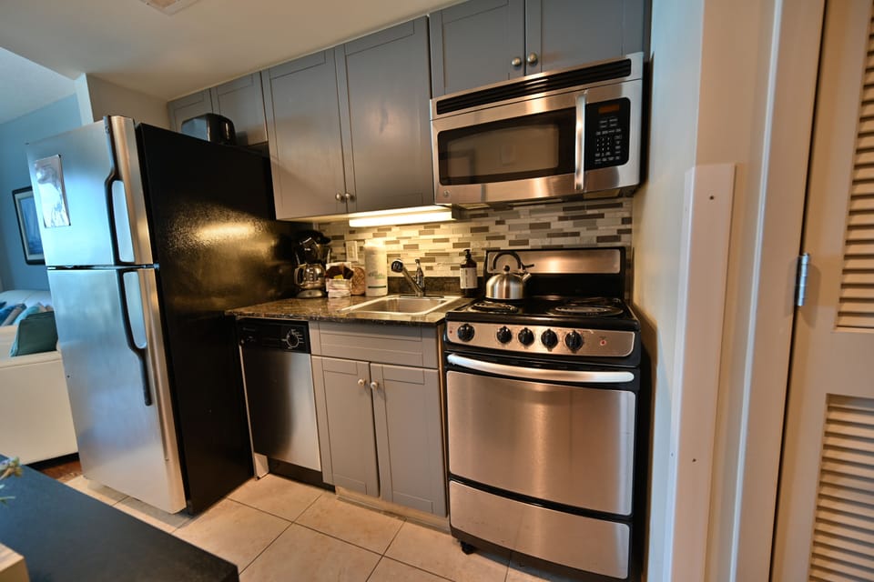 Modern kitchenette with stainless steel appliances, stylish backsplash