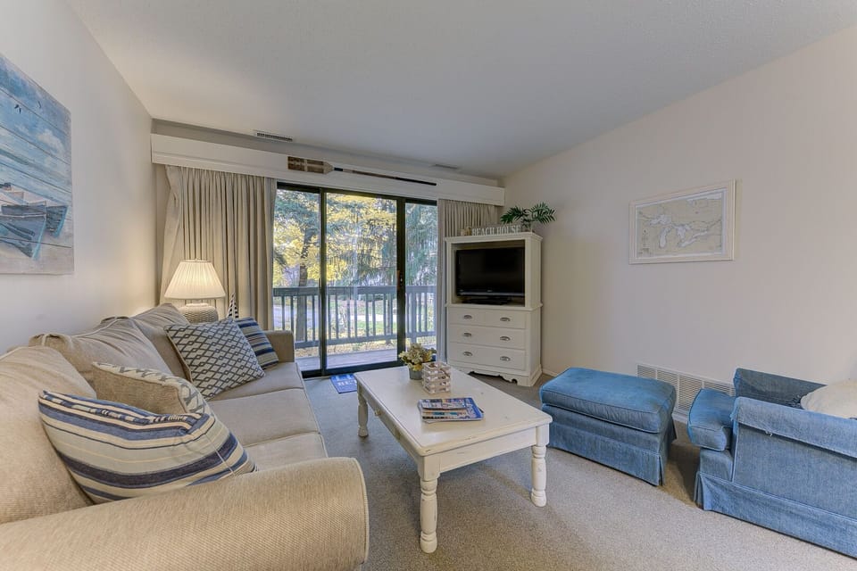 The living room is adorned with a balcony, a smart TV. Adding to the comfort, there is a single sofa accompanied by a footrest.