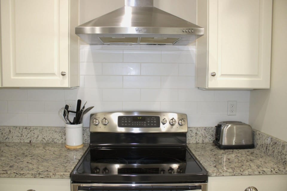 Sleek stainless steel stove with a modern range hood and granite countertops!