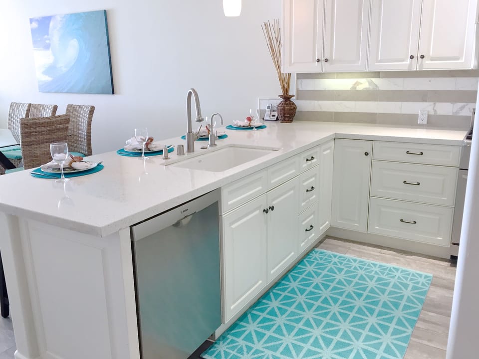 White, bright kitchen with quartz countertops.