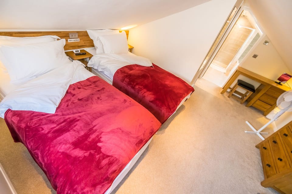 The upstairs bedroom has two single beds and a smart TV. 