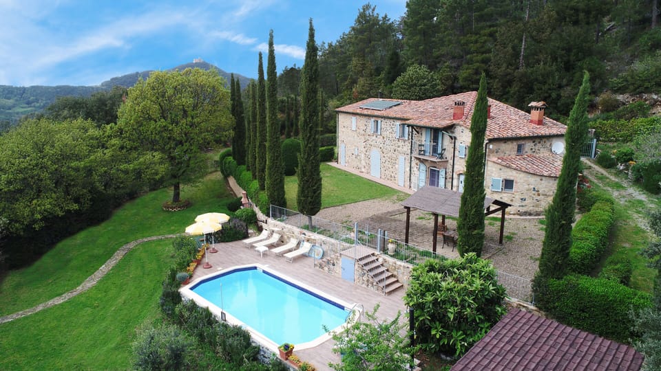 The villa, the swimming pool, the cypresses and  the fortress Rocca Sillana