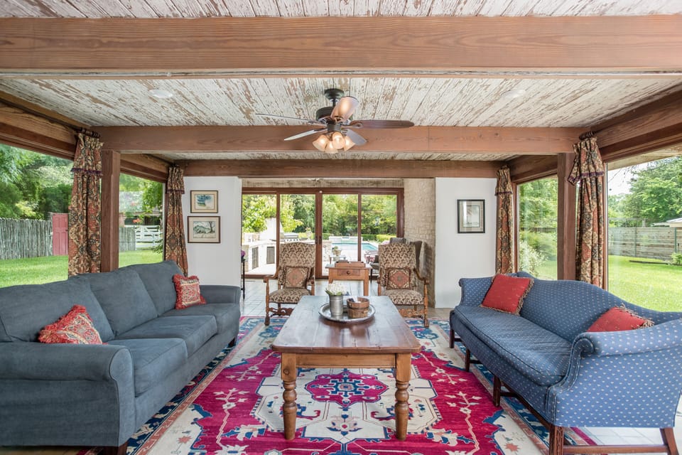 Living room has TV, seating for 10, & floor to ceiling windows onto pool & yard