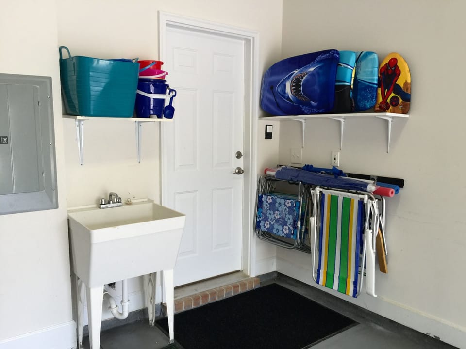 Garage stocked with chairs, umbrella, boogie boards, and beach toys. More inside