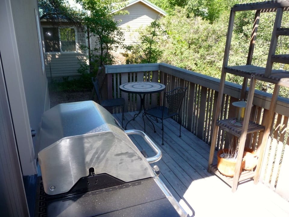 Back deck with a small table, chairs and BBQ.  Stairs lead to the hot tub.