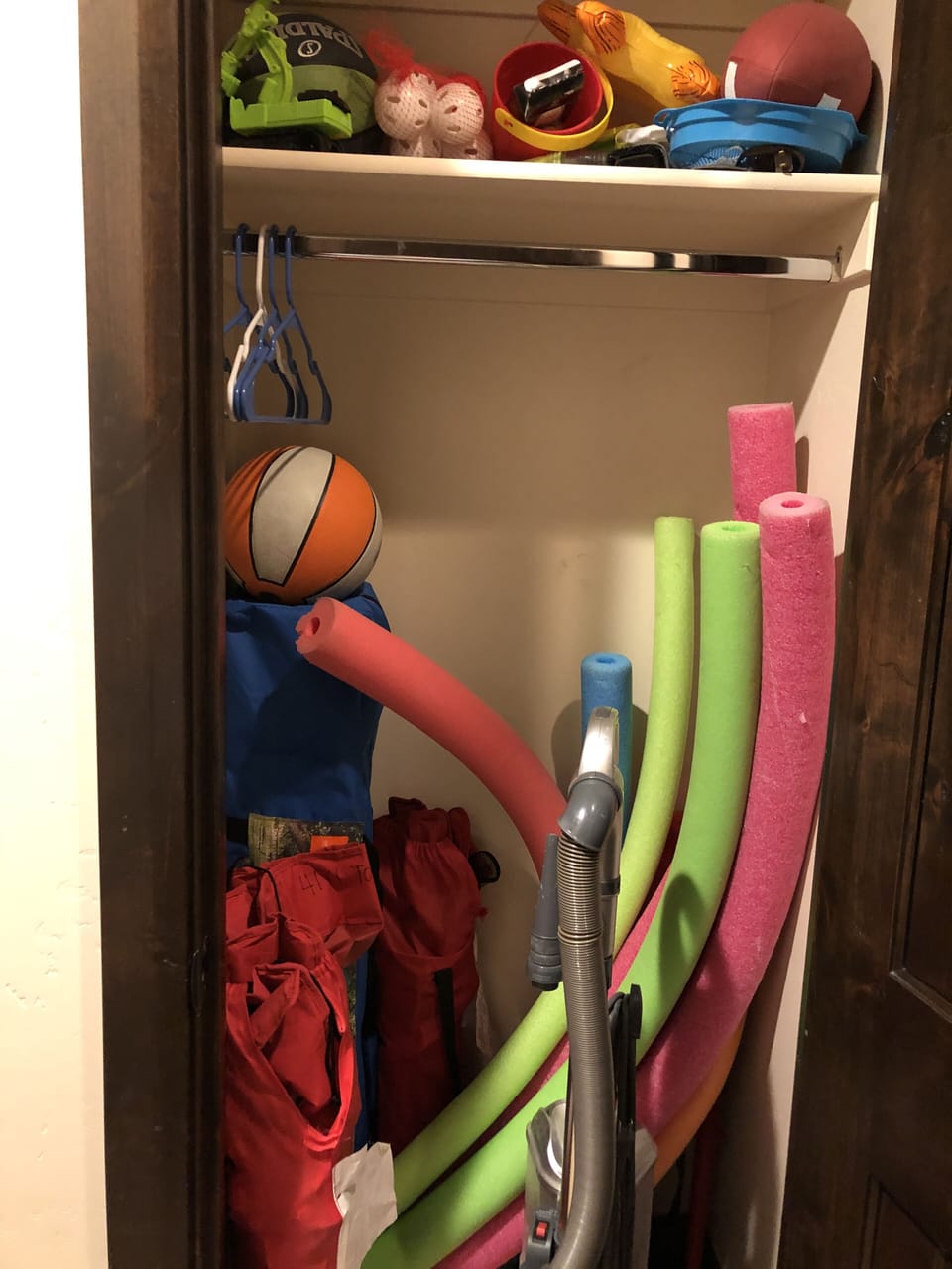 Hall closet stores sport and pool toys, camp chairs, vacuum and pop up canopy.