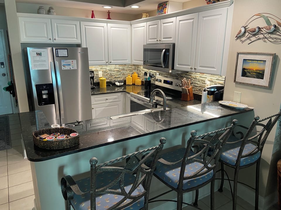 Open view into kitchen from Dining Room. Bar & bar stools.