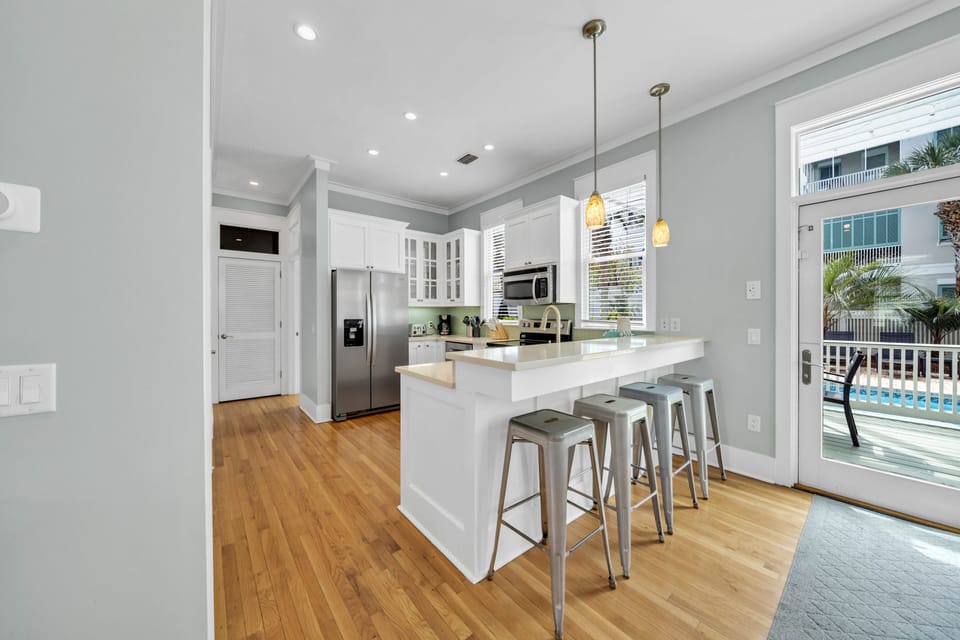 This Large White Kitchen Features Stainless Steel Appliances and  Breakfast Bar With Seating for 4