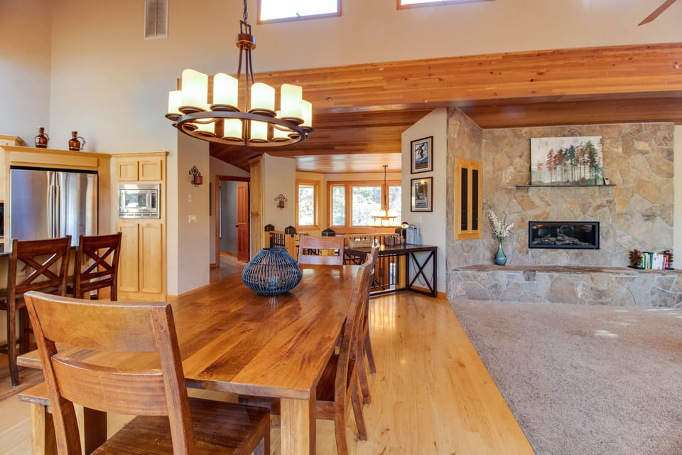 View of 10 person dining, desk, front entry beyond. 4 addl. stools at counter.