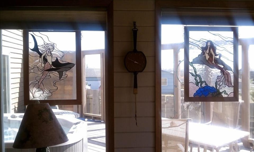 Two beautiful stained glass mermaid panels in the living room windows.