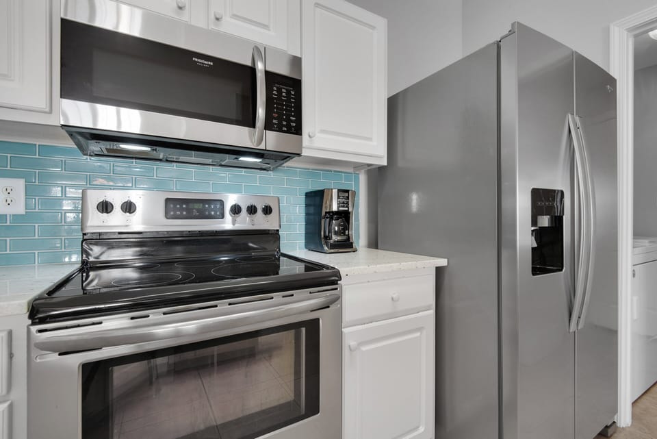 Close-up of stainless steel oven, microwave, fridge, and coffee maker