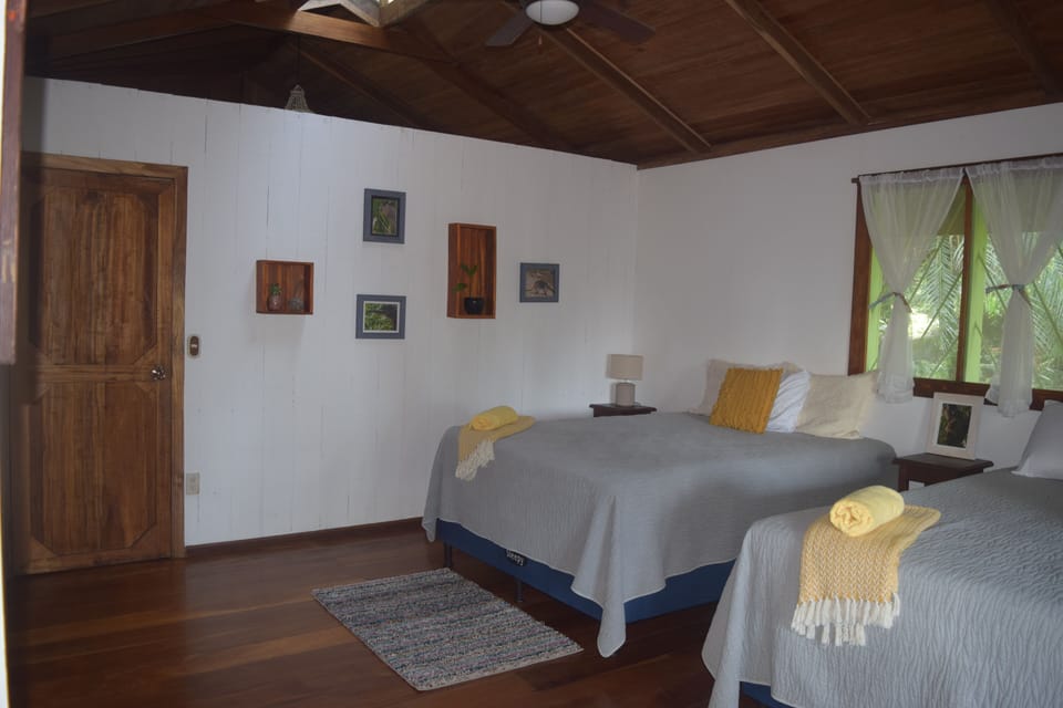 Bedroom on main floor with 2 queen beds, private entrance to bathroom & balcony.