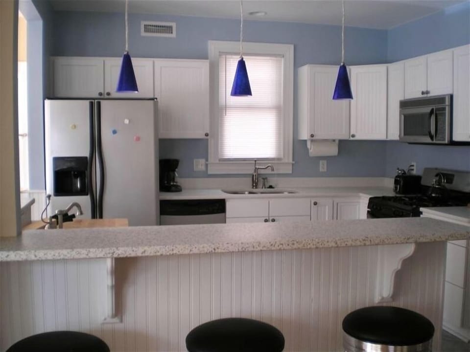 kitchen with bar seating area, granite tops, 2 sinks, stainless steel appliances