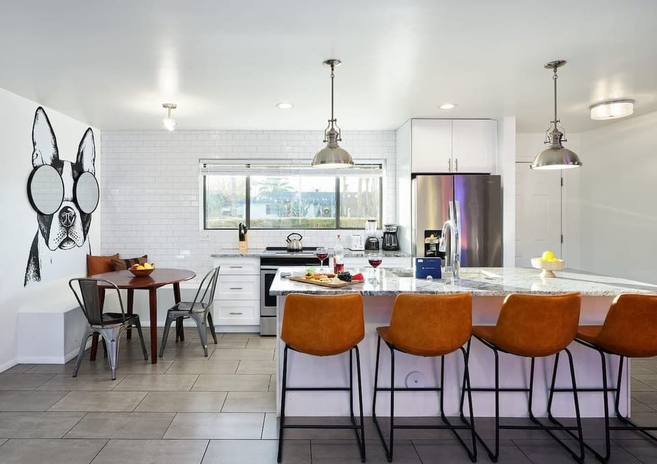 Bright and open kitchen supplied with your basic cooking essentials, stainless steel appliances, breakfast bar seating,  and breakfast nook. Features custom mural Frenchie!