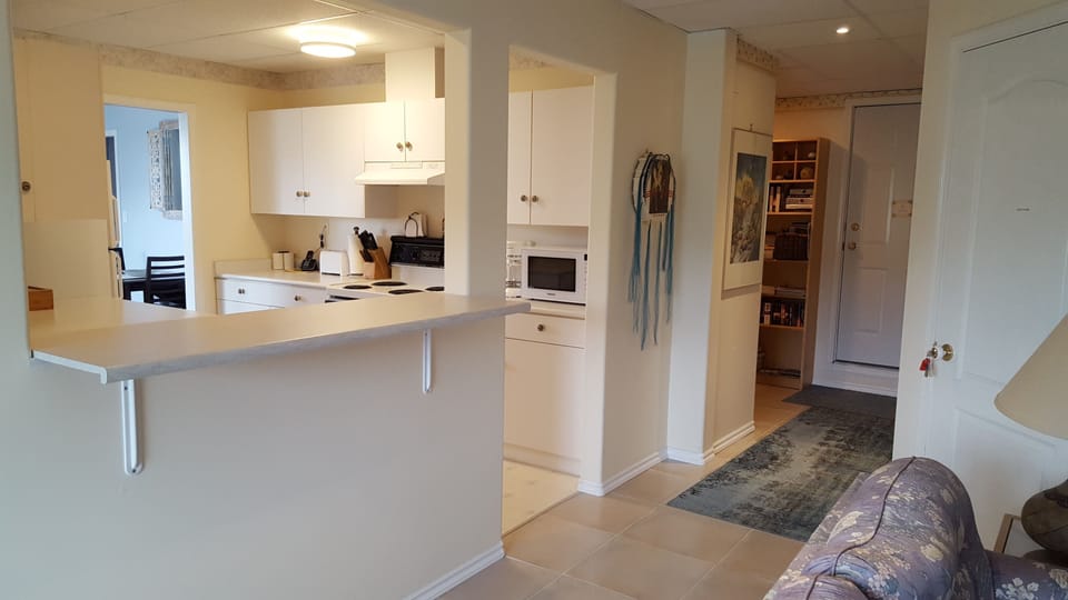 Looking into full kitchen from living area (and down hallway to the bedroom)