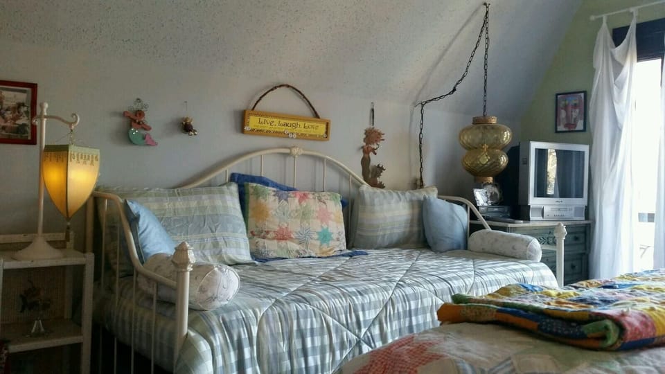 Upstairs lakeside bedroom has a daybed and a queen. Seating, closet and balcony.