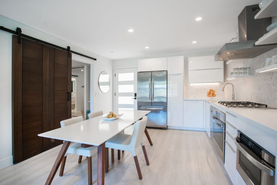 LARGE, CUSTOM QUARTZ & WALNUT TABLE.   REVEALS SLIDER BARN DOOR TOWARD BEDROO