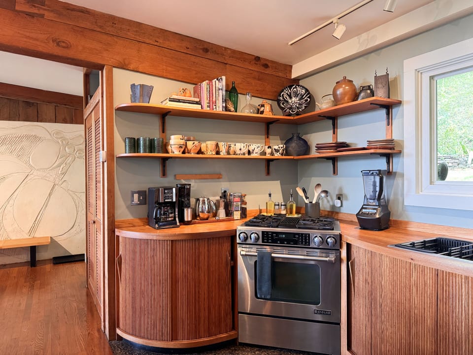 Warm designer kitchen with gas range, open shelving, and coffee station
