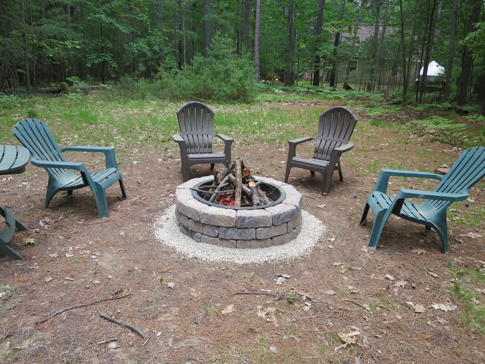 Fire-pit with chairs are in the backyard.