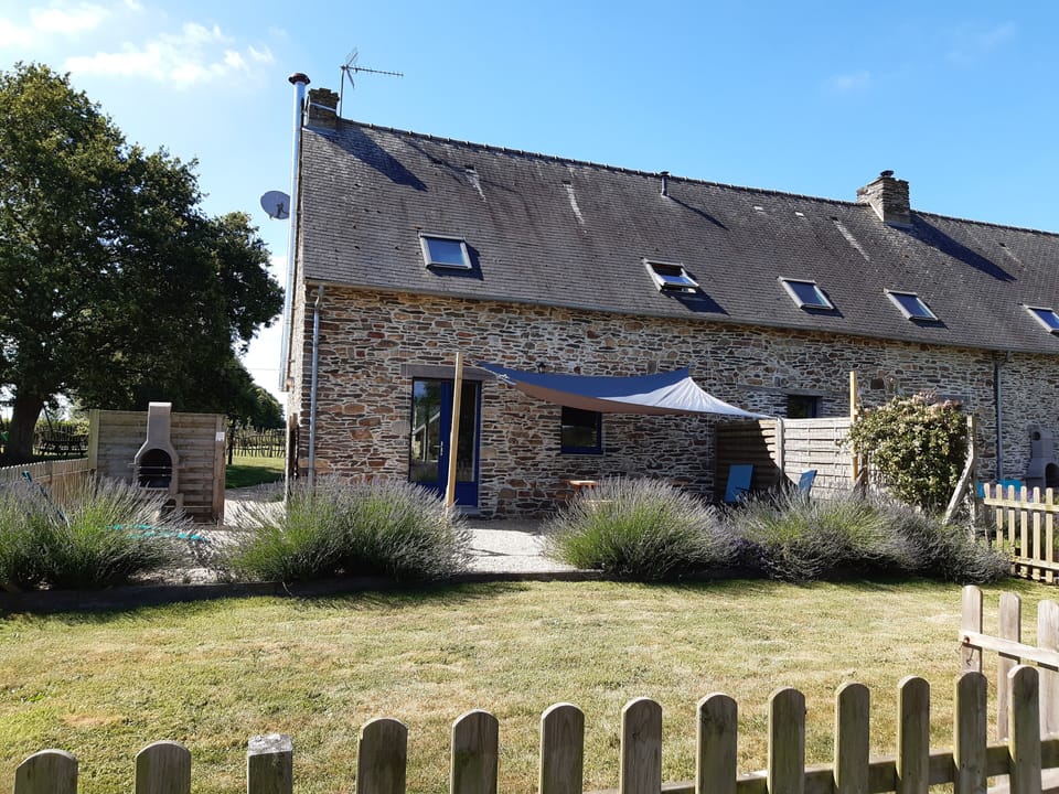 Jardin clos avec patio, voile d'ombrage, coin repas extérieur et barbecue.
