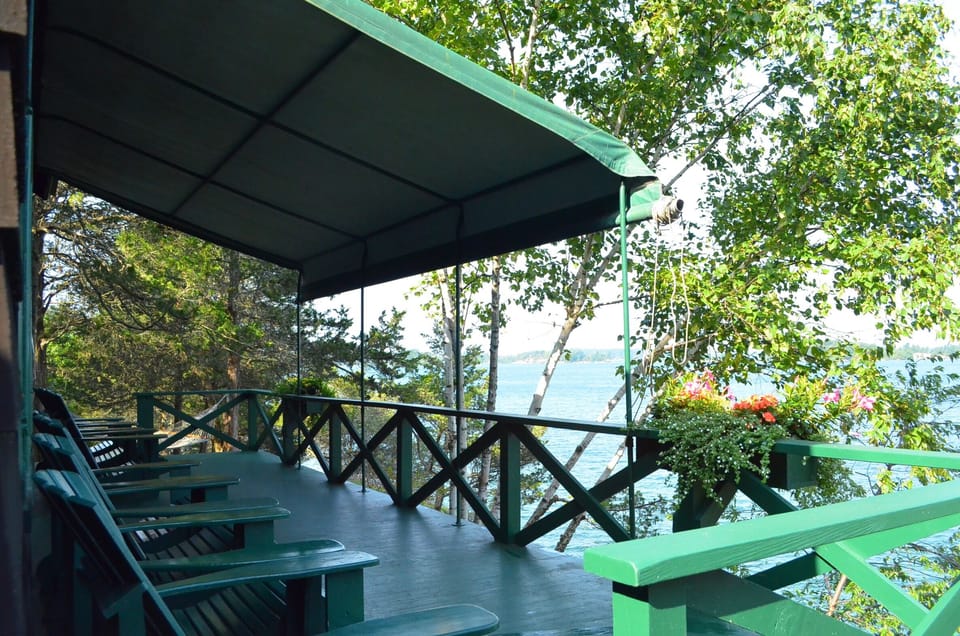 Adirondack chairs adorn the porch. The awning provides shade on hot summer days.
