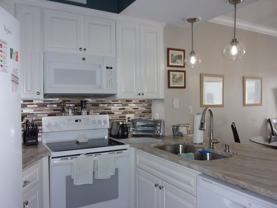 A full kitchen under cabinet lighting and granite.