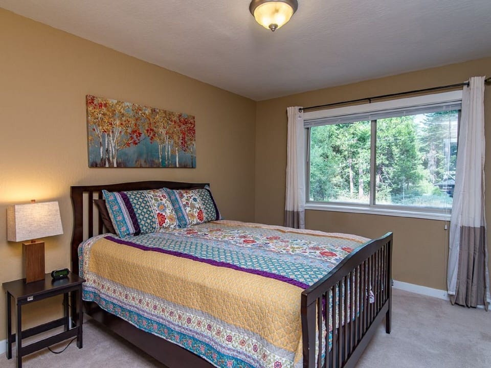 A bedroom comes with a queen bed and a colorful, floral pattern quilt.