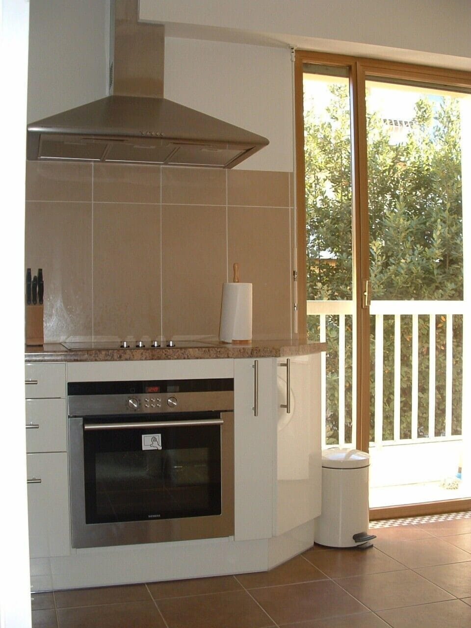 Kitchen with full amenities. Door opens to narrow balcony with sea view.