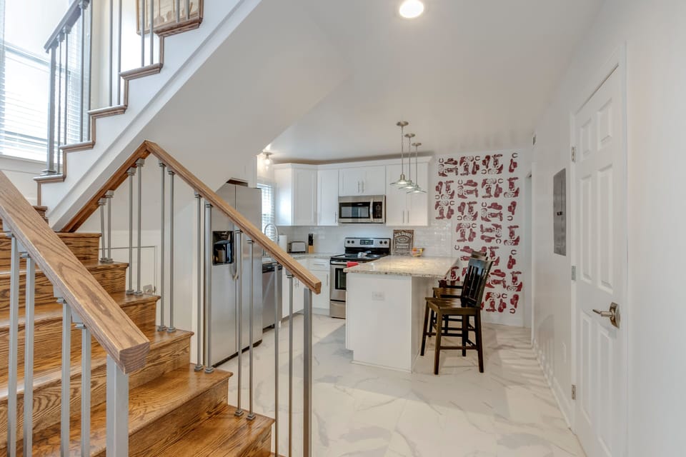 Modern white kitchen with granite island, stainless appliances & seating