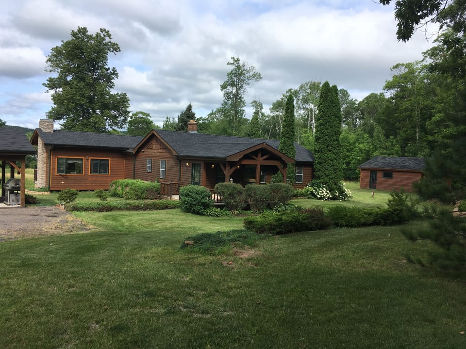 Front of home on 10 acres with lawn for outdoor games and trails nearby.