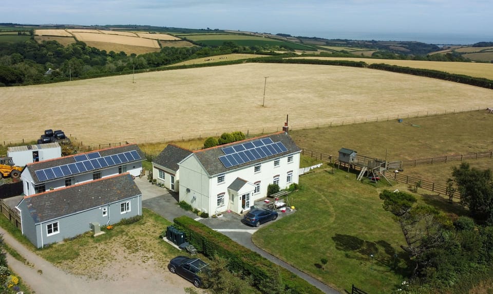 Aerial view of the farmhouse and cottages with Start Bay in the distance