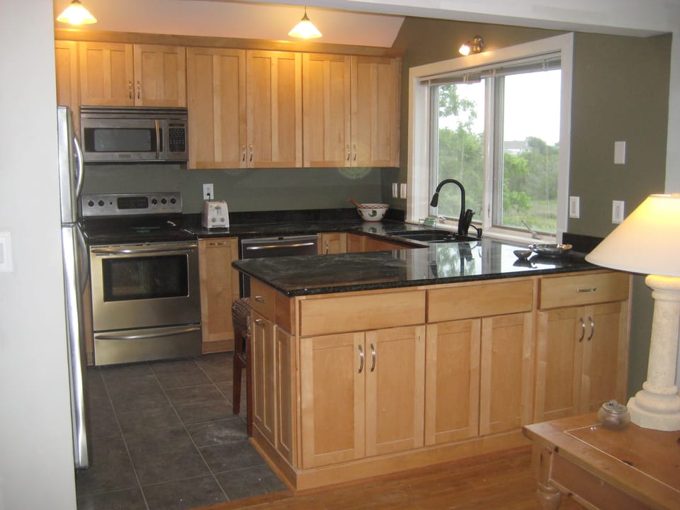 Fully furnished kitchen with seating for 5 at the granite counter, grill on deck