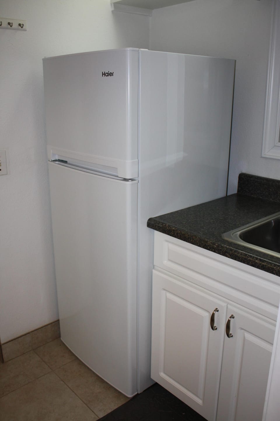 Galley kitchen has large sink and family size refrigerator with separate freezer