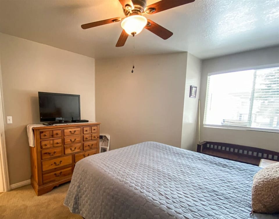 Sunny bedroom retreat with cozy bedding, ample storage, and a TV for ultimate relaxation.