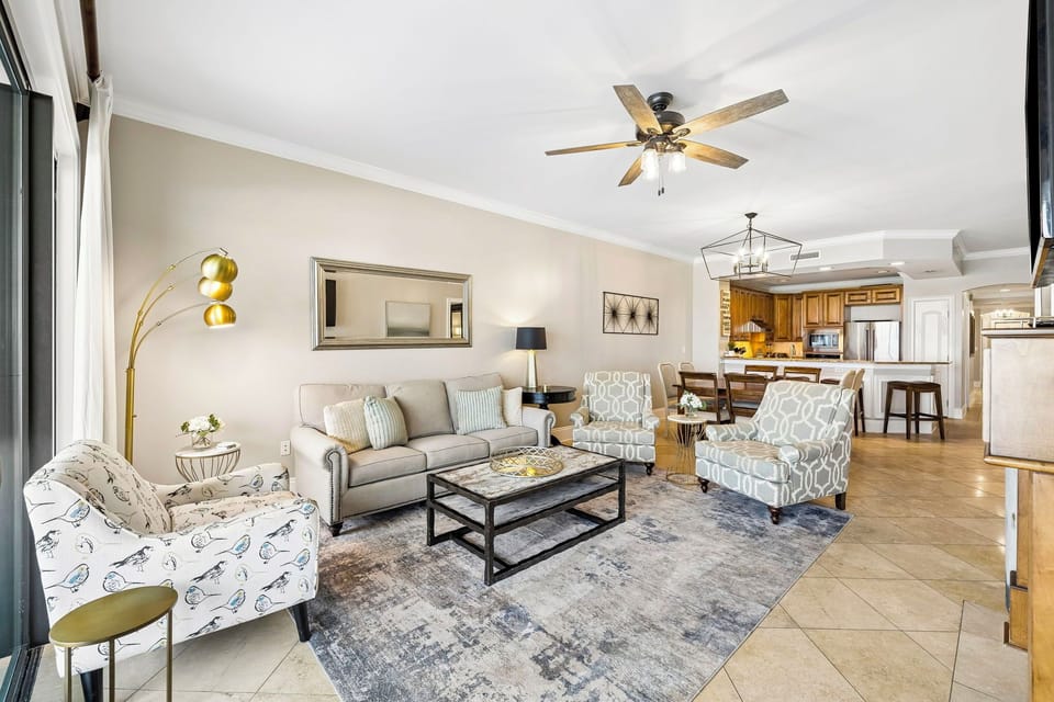 Step into your open-concept living space, where coastal elegance meets comfort. Relax on plush seating under a vaulted ceiling with ceiling fan, or gather around the fully-equipped kitchen for memorable meals together.