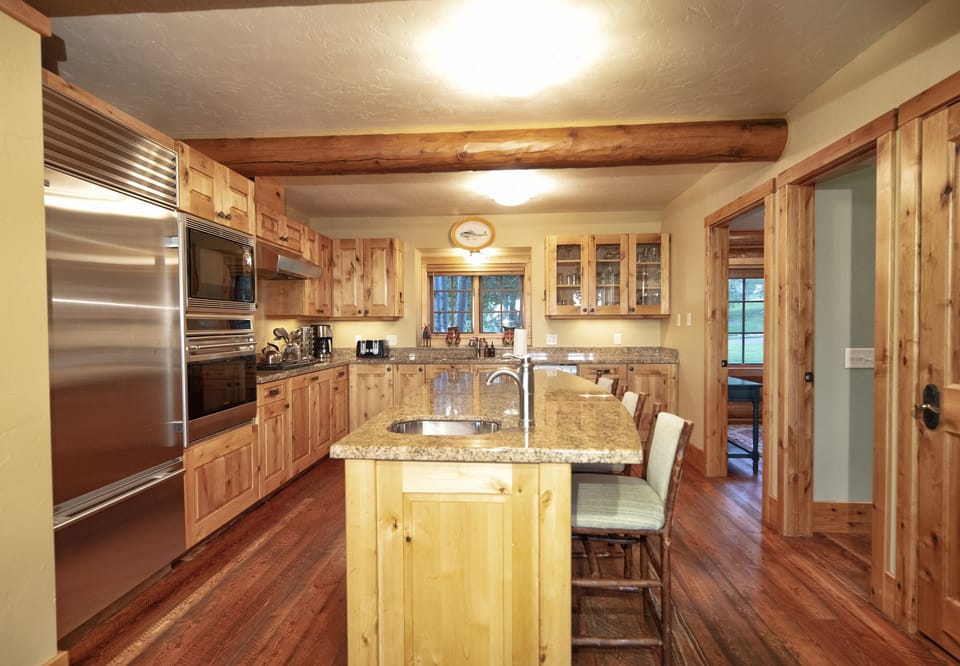 Your chef's haven awaits with warm wood cabinets, granite counters, and stainless steel appliances. The spacious island invites morning coffee chats while exposed beams overhead add rustic charm.