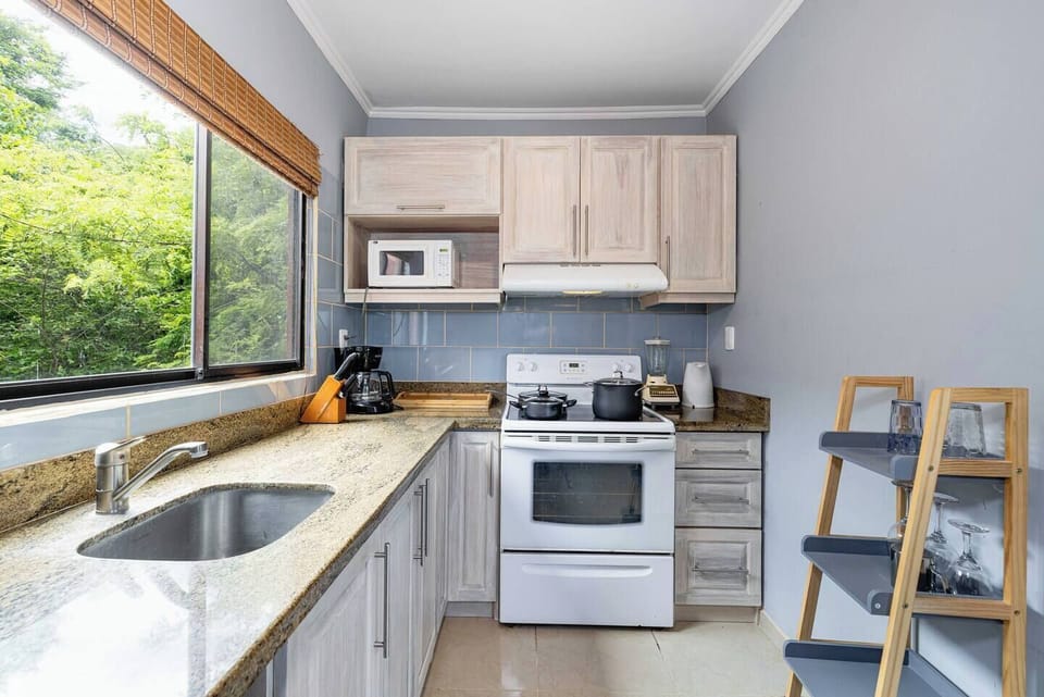 Well-equipped kitchen featuring an electric stove with oven, refrigerator, microwave, blender, coffee maker, and all essential cookware—perfect for preparing meals during your Tamarindo vacation rental stay.