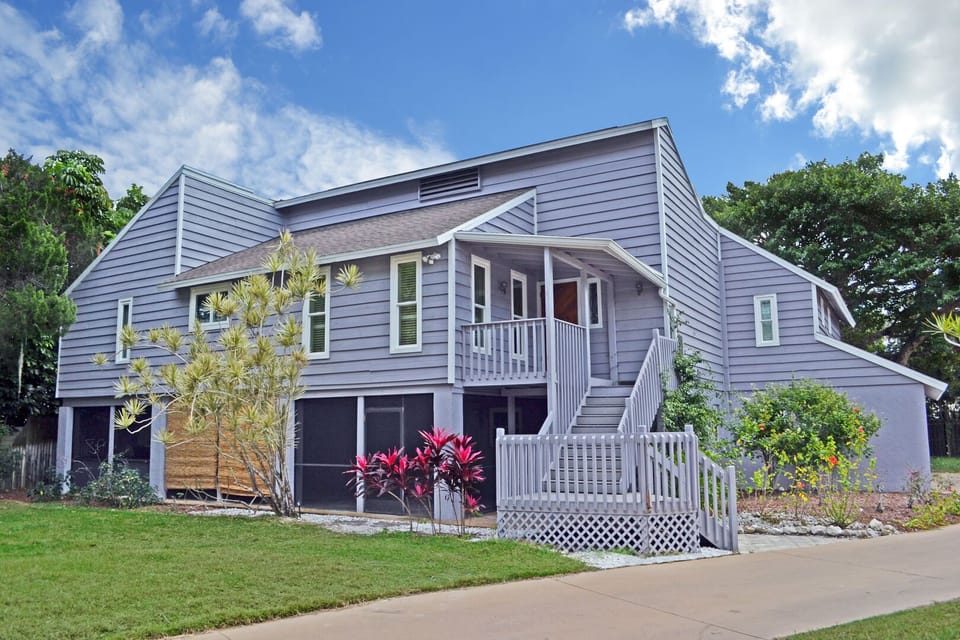Front facade of the two-story treehouse-style home with dark wood shingles and lush landscaping