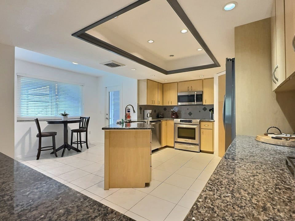 Open-plan kitchen and dining area with island seating, stainless appliances, and dining table