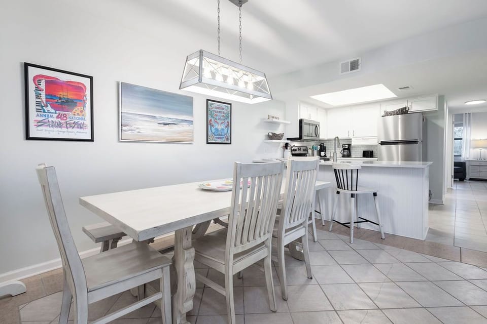 Dining Area - Enjoy meals at the stylish table that comfortably seats six, enhanced by a charming bench for additional guests. Plus, two bar stools at the adjacent bar create the perfect spot for casual dining or morning coffee.