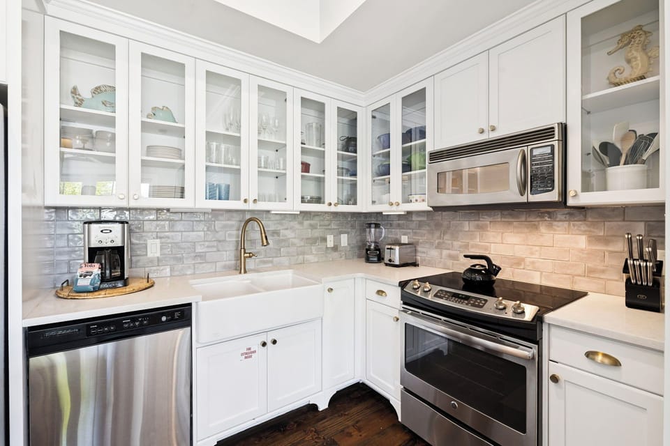 Your bright, modern kitchen features gleaming white cabinets, elegant marble subway tile, and premium stainless steel appliances ready for your culinary adventures.